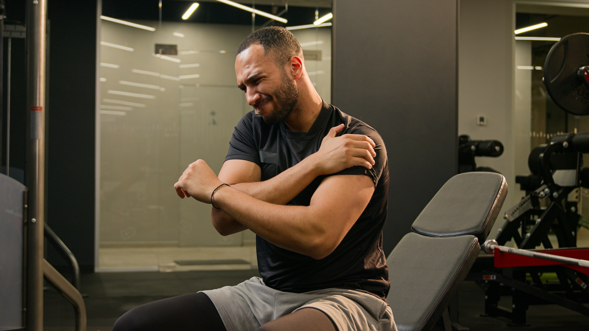 Latino ethnic multiracial American strong man sitting in gym press lift dumbbells up heavy metal