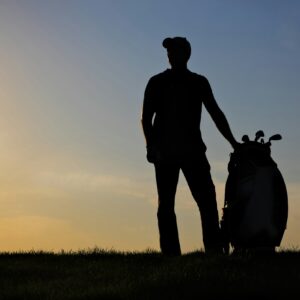 Male golfer playing golf at sunset